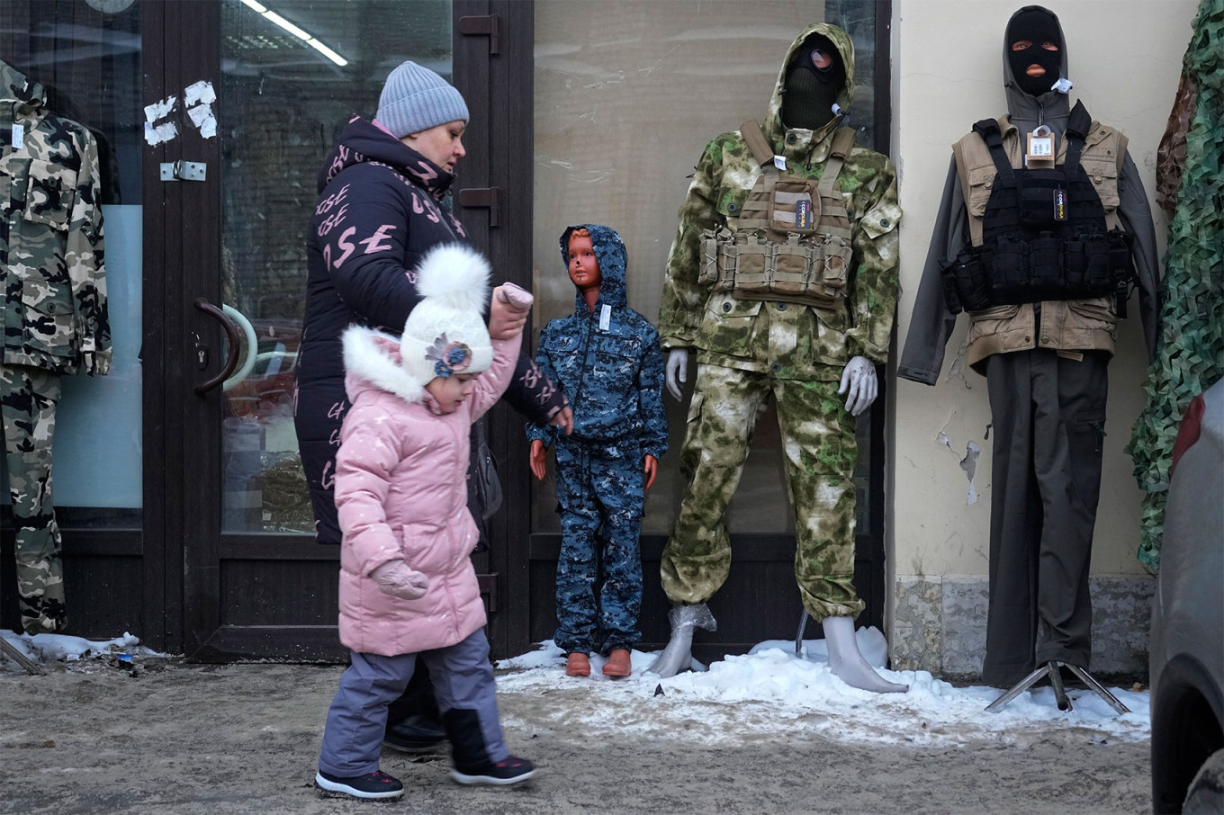 O femeie trece cu copilul ei pe lângă un magazin de haine de camuflaj din Sankt Petersburg. Sursa foto: The Moscow Times