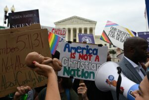 Militanți pentru dreptul la avort și activiști anti-avort, inclusiv Terrisa Bukovinac, care ține în mână un făt fals, demonstrează în fața Curții Supreme Sursa foto The Washington Post