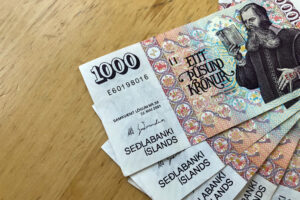 Mai multe bancnote de 1000 de coroane islandeze pe o masă de lemn. Coroana islandeză este moneda națională a Islandei 
