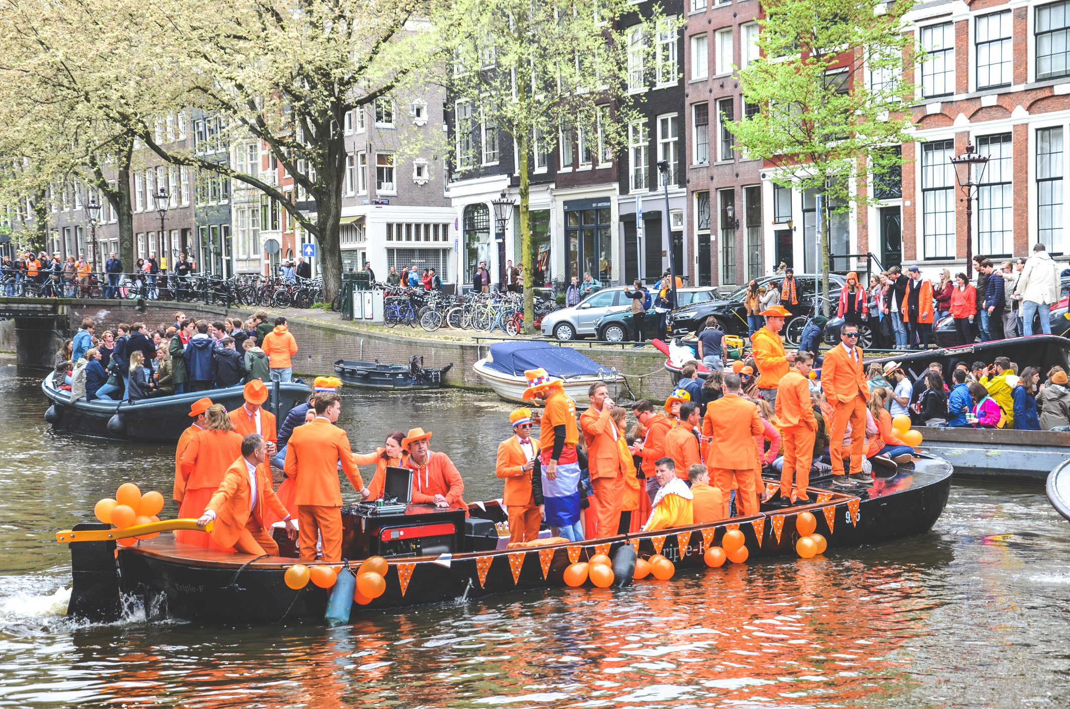 Amsterdam, Olanda - 27 aprilie 2019: Oameni pe bărci de petrecere îmbrăcați în culoarea națională portocalie în timp ce sărbătoresc ziua regilor, Koningsdag, ziua de naștere a regelui olandez Willem-Alexander. Sursă foto: Dreamstime