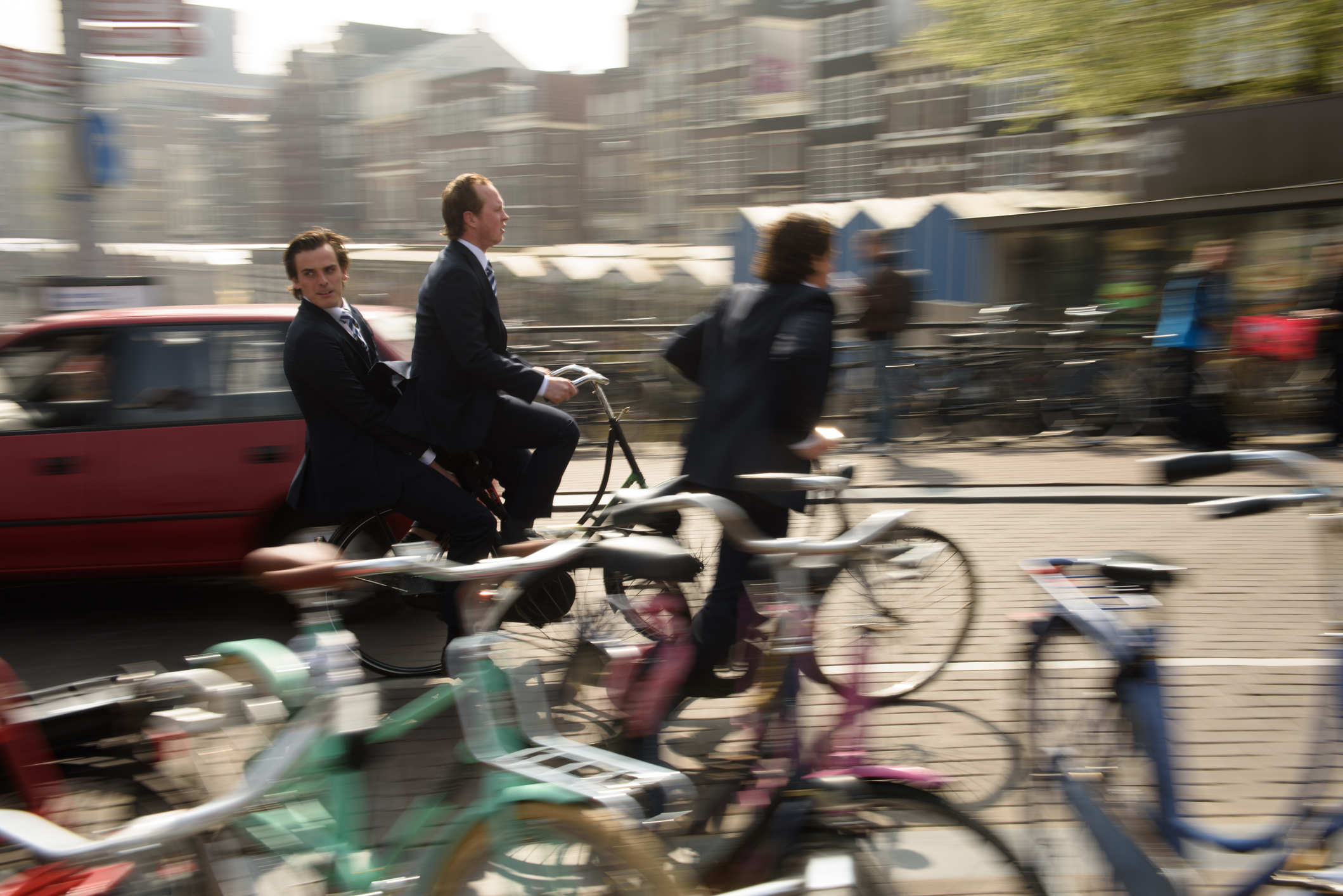 Amsterdam, Olanda, aprilie 2015: Tineri în costum și cravată merg pe bicicletă la serviciu pe străzile aglomerate din Amsterdam. Mersul pe bicicletă pe străzile orașului Amsterdam este o formă de transport foarte populară pe tot parcursul anului. Sursă foto: Dreamstime