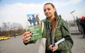 O tânără voluntară ține în mână unul dintre pliantele promoționale pe care le împarte oamenilor de pe stradă.