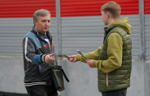 Un voluntar înmânează un pamflet de promovare a serviciului militar profesionist unui bărbat de vârstă mijlocie.