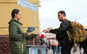 Un tânăr primește o broșură despre înrolarea în armata rusă ca soldat profesionist.