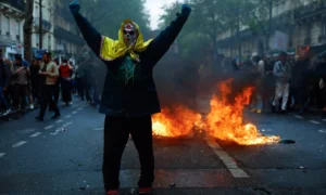 Oamenii sărbătoresc pe străzile Parisului, în timp ce protestele din acest an de 1 Mai coincid cu un șir lung de indignare publică legate de o lege privind reforma pensiilor (sursă foto: The Guardian)