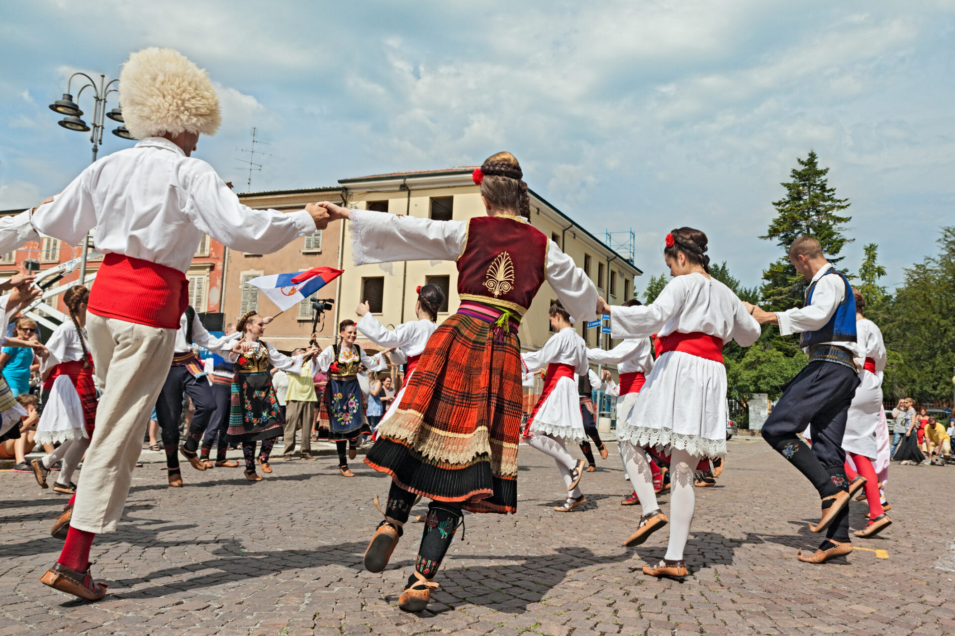 Grupul de dansuri populare numit „Ansamblul folcloric Biserica Sfântul Gheorghe” din Belgrad, Serbia, este cunoscut la nivel național pentru dansurile populare în cerc, pe modelul horei, în haine tradiționale. Această fotografie a fost făcută la Festivalul Internațional de Folclor din Russi, pe 3 august 2014 în Russi, Italia (sursă foto: Dreamstime)